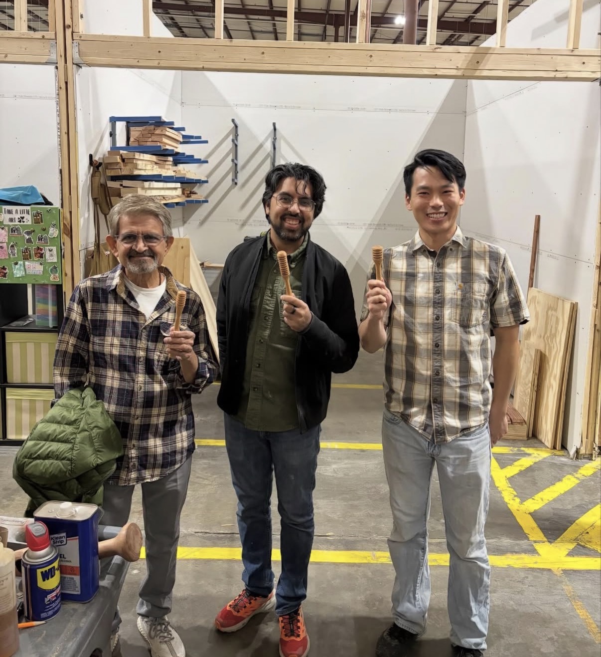 Three students holding honey dippers they turned in a beginner class